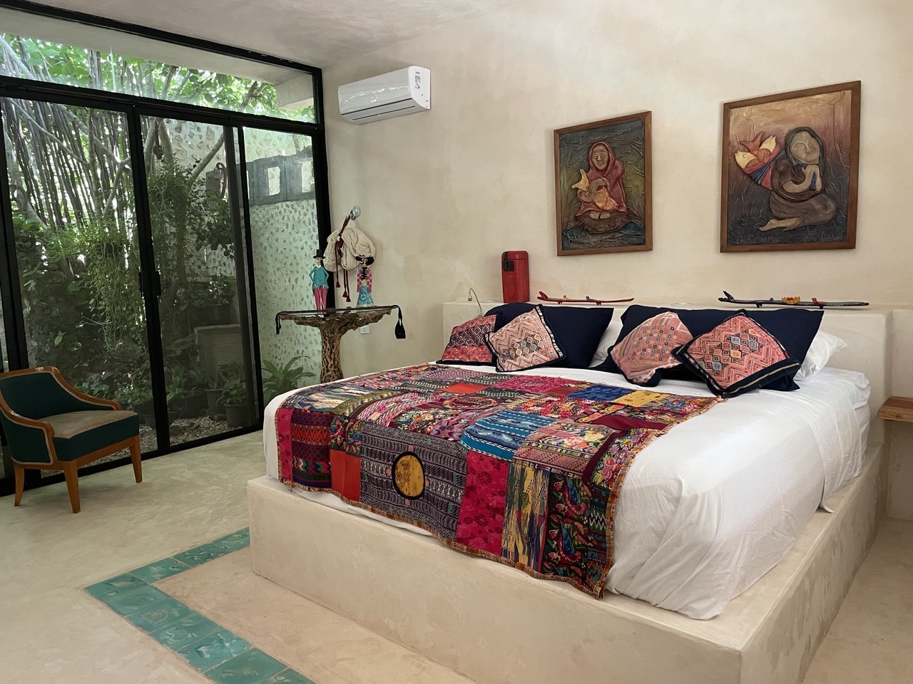 Suite Helecho con cama grande, colcha colorida y ventanal al jardín