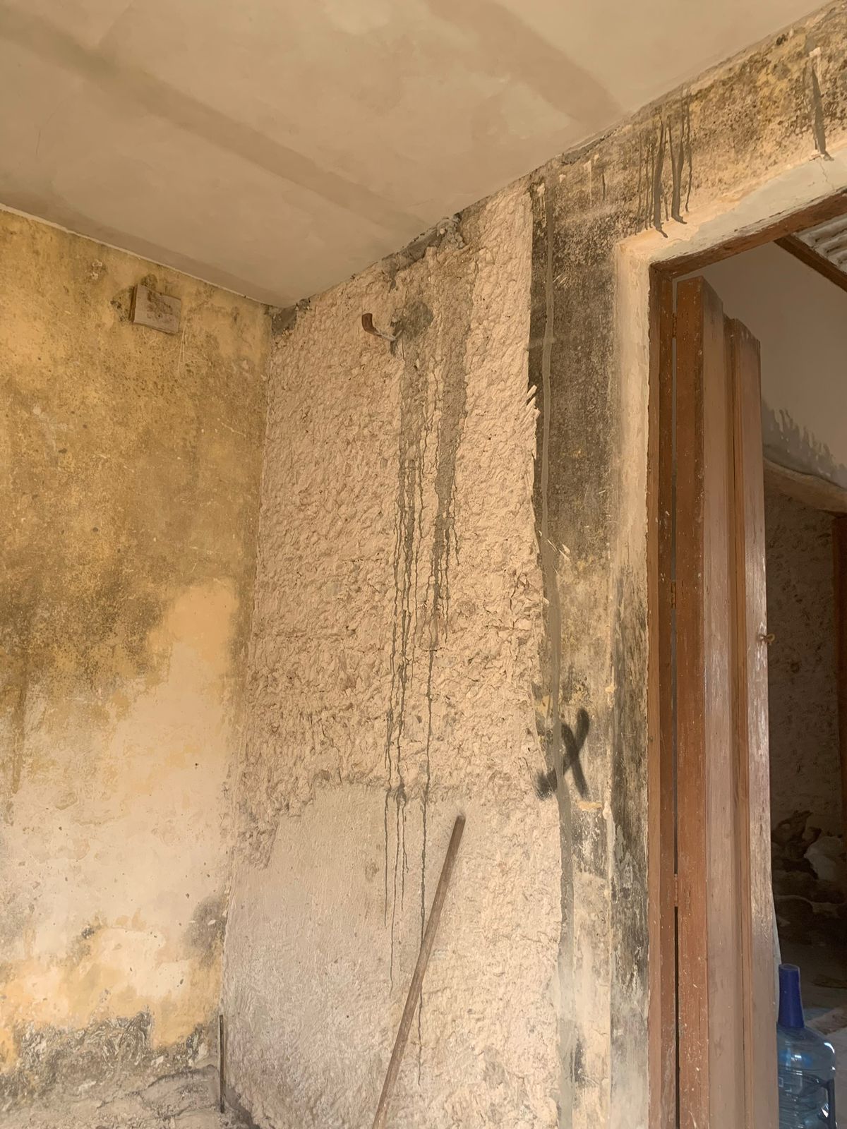 Paredes de una habitación en construcción o remodelación con yeso y marcas de humedad.