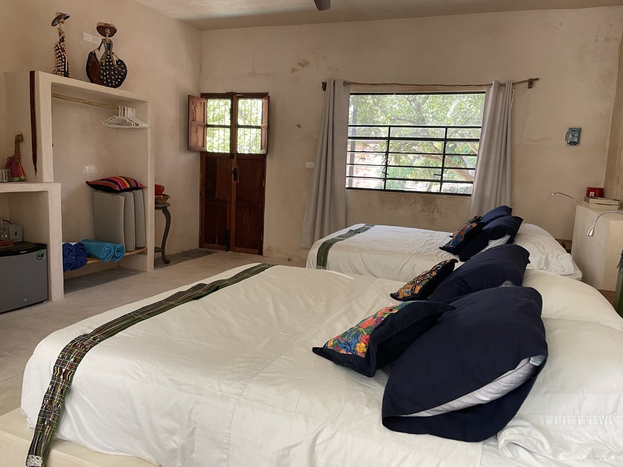 Habitación con dos camas, ventana con vista al exterior y un armario abierto.