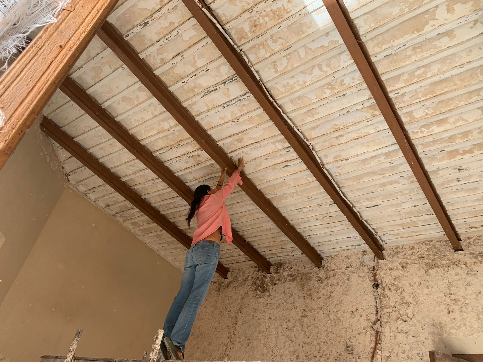 Persona trabajando en el techo de un espacio en construcción con vigas de madera.