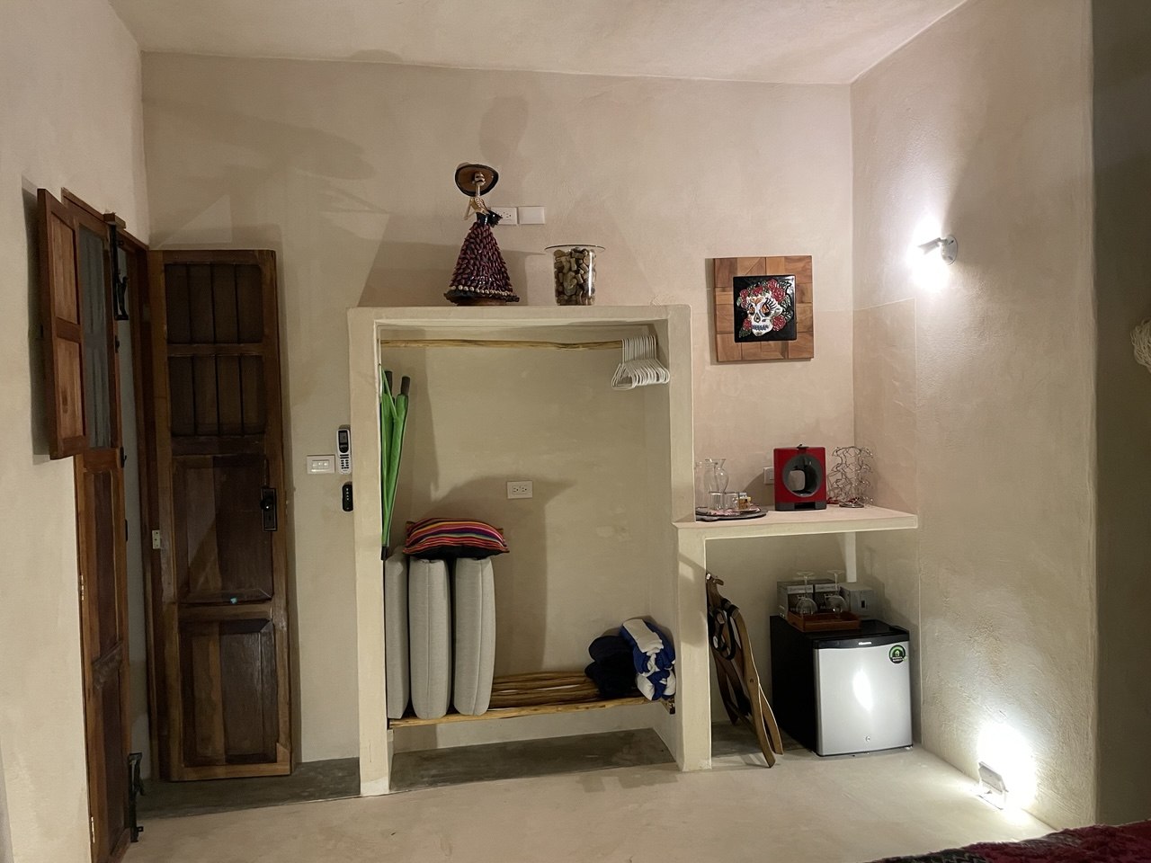 Habitación con armario abierto, mini nevera, cafetera y decoración de calavera.