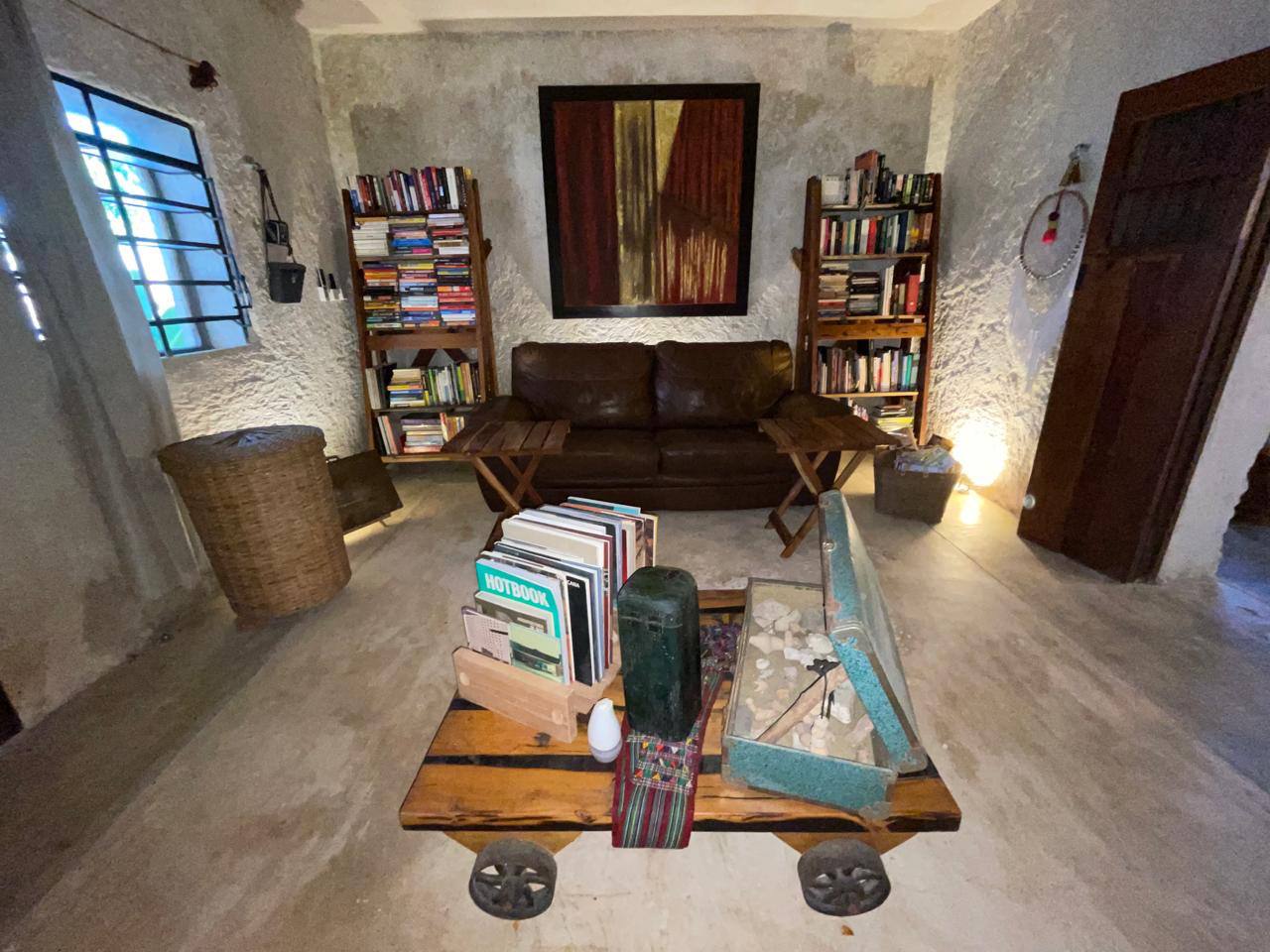 Sala con sofá de cuero, estanterías llenas de libros y mesa de centro de madera.